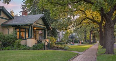 Family walking through a tree-lined neighborhood in suburban Portland Oregon with well-maintained homes and green parks