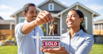 Keys being handed to a new homeowner in front of a brand-new construction home in Oregon with a SOLD sign
