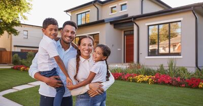 Familia hispana frente a su nueva casa en una comunidad residencial de Portland Oregon con jardín bien cuidado