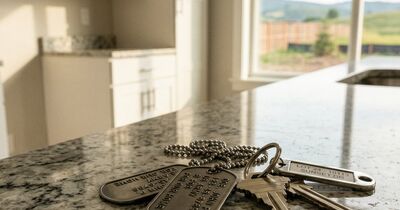 Military dog tags resting on house keys on a granite countertop in a new-construction home