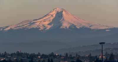 Mount Hood rising above the Portland metro area in hazy late summer evening light